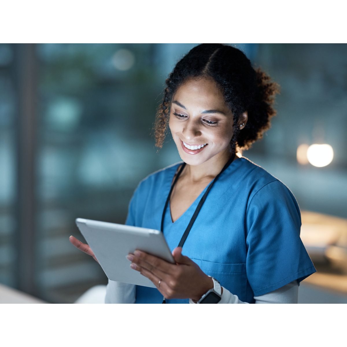 A healthcare professional in scrubs reviewing findings on a tablet