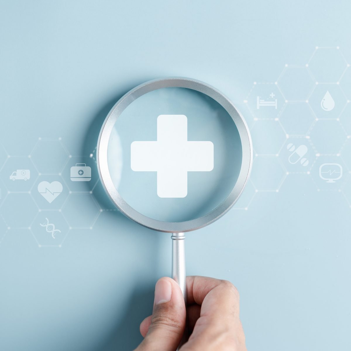 A magnifying glass highlighting a medical cross icon, representing research and insight